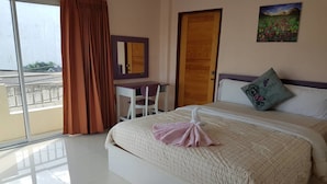 Ein Hotelzimmer mit Bett, Schreibtisch, Stuhl, einem großen Fenster mit Vorhängen und einer Tür.