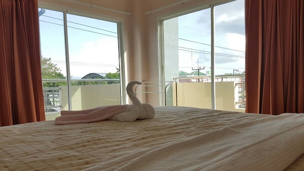 Ein Hotelzimmer mit Bett, einem schwanenförmigen Kopfkissen und großen Fenstern mit Blick auf die Stadt.