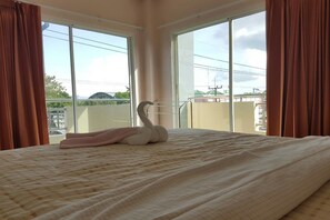 A hotel room with a bed, a swan-shaped pillow, and large windows offering a view of the cityscape. - V-House Hotel (Trang)