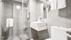 A modern bathroom with a glass-enclosed shower, a white sink, and a toilet. - Trans Inn (Taichung)