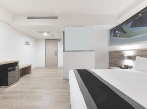 Ein modernes Hotelzimmer mit Bett, Nachttisch, Lampe und einem Bild an der Wand.