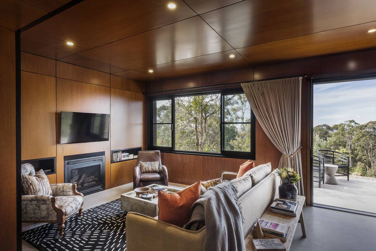 Un salon moderne doté d’une cheminée, de sièges confortables et d’une grande fenêtre offrant une vue sur l’extérieur.