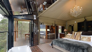 Ein geräumiges Schlafzimmer mit einem großen Bett, einer Badewanne und einem Balkon mit Holzboden.