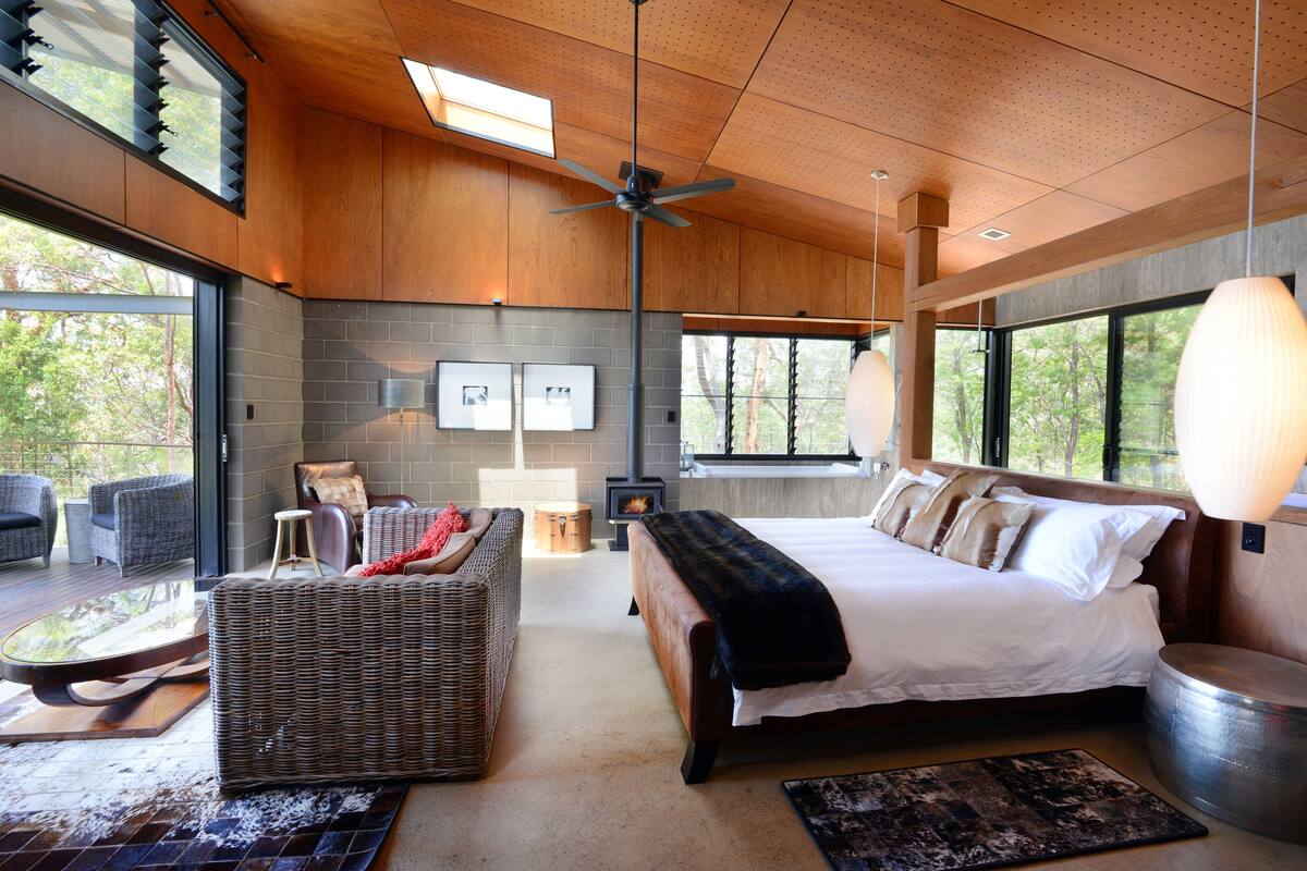Une chambre moderne avec un grand lit, une cheminée et une vue sur l’extérieur.