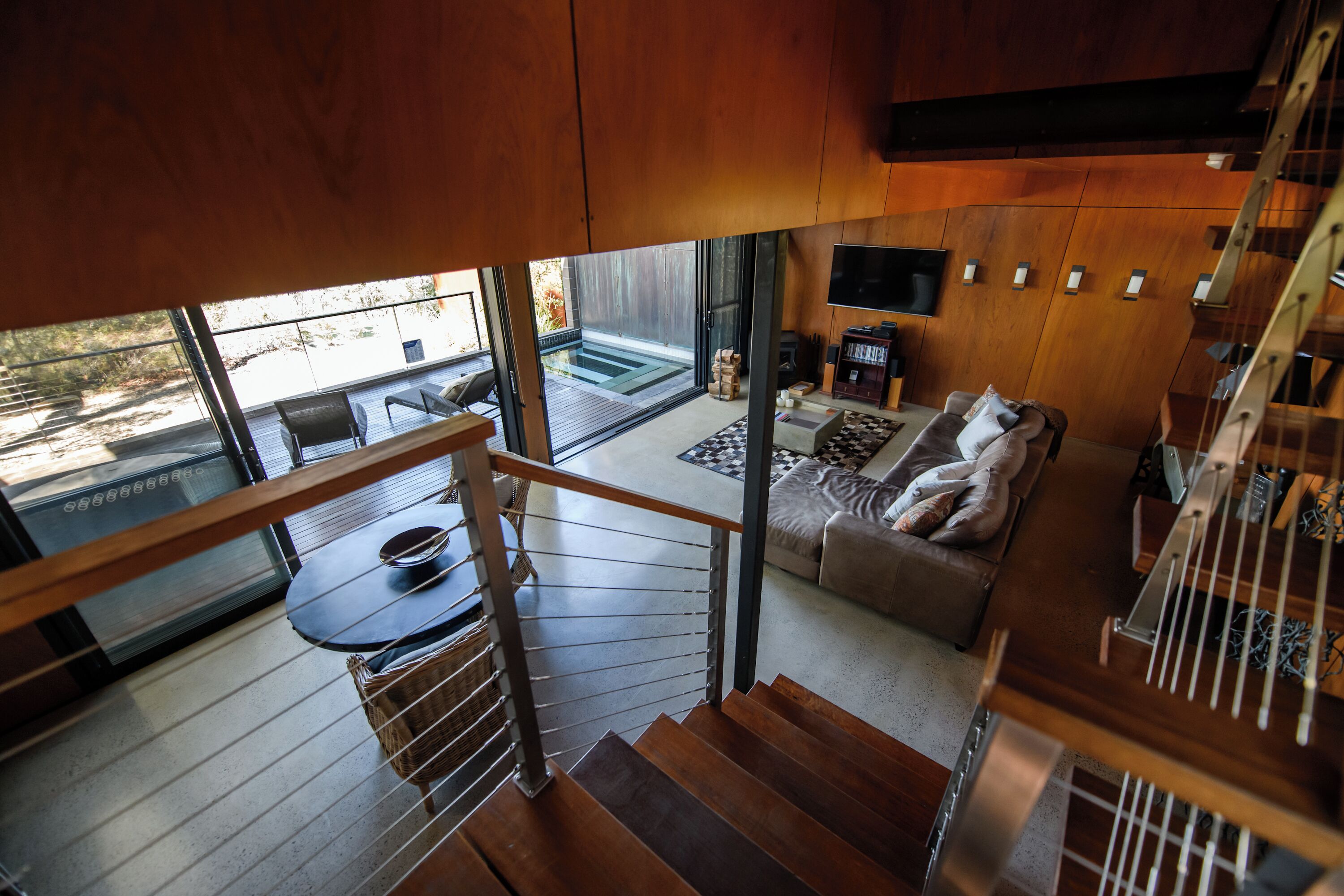 Un interior moderno con una escalera que lleva a una sala de estar, una mesa de comedor y un sofá.