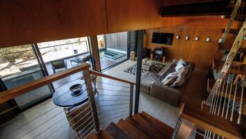 Un interior moderno con una escalera que lleva a una sala de estar, una mesa de comedor y un sofá.