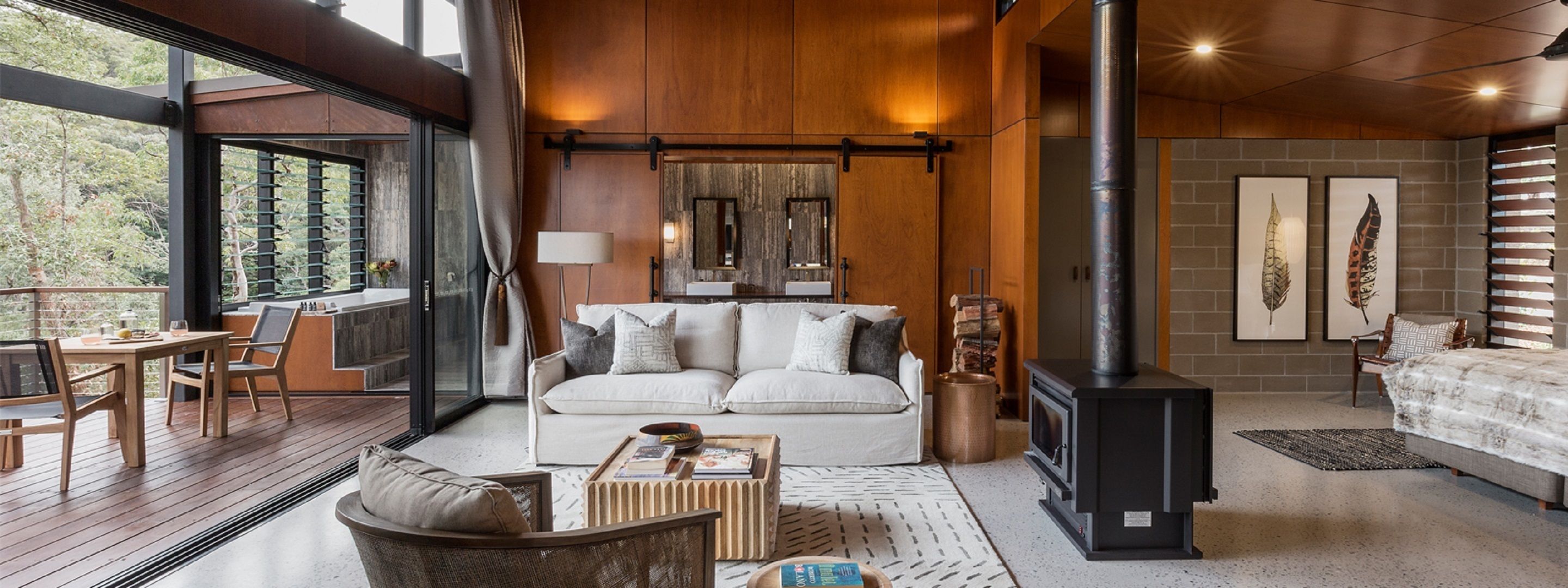 Een gezellige woonkamer met een bank, salontafel en open haard. Er is een eethoek met een tafel en stoelen, en een groot raam met uitzicht op de omgeving.