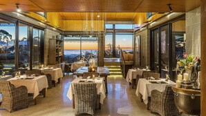 Ein Restaurant mit gedeckten Tischen, großen Fenstern und Blick auf die Landschaft.