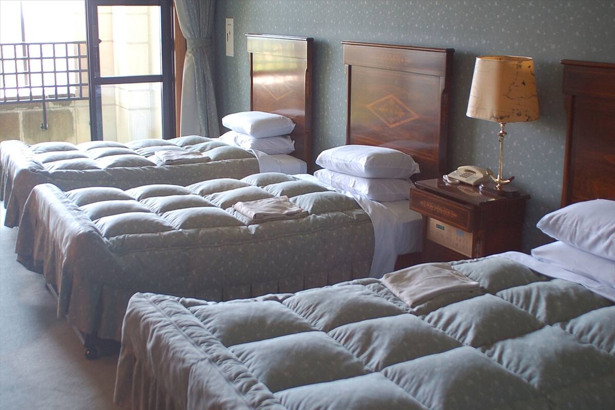 Ein Hotelzimmer mit mehreren Betten, einem Nachttisch mit Lampe und einem Telefon.