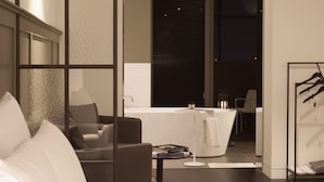 A modern hotel room with a large bed, a seating area with a table and chairs, and a view of the city at night. - Hotel Gaden by Onyu stay (Suwon)