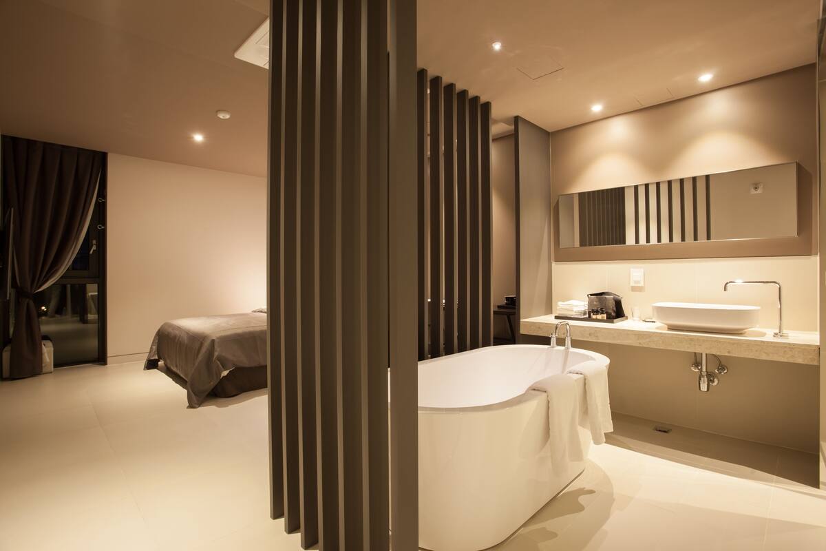 Une salle de bain moderne avec une baignoire sur pieds, un grand miroir et un meuble-lavabo.