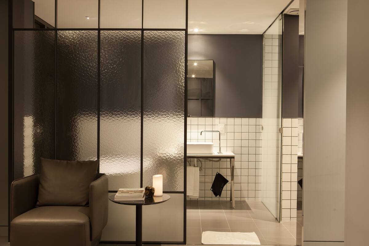 Une salle de bain moderne avec une paroi en verre, un lavabo et une chaise.