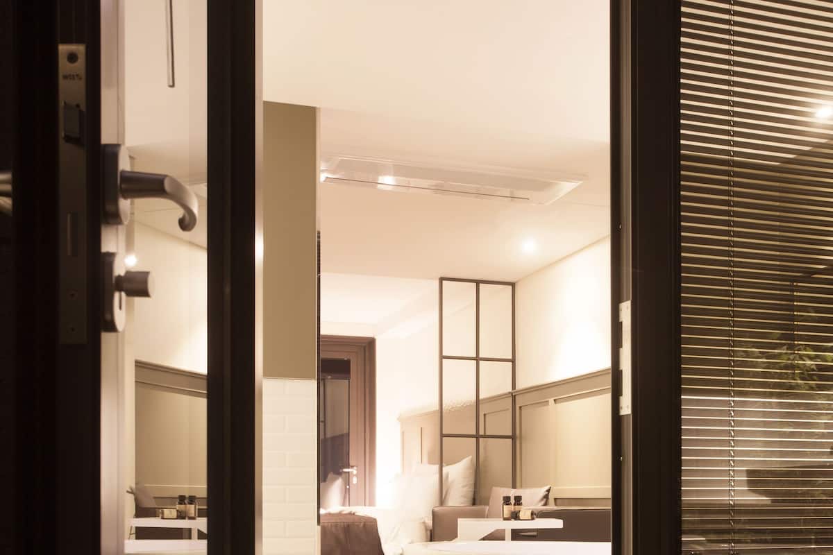 Une chambre d’hôtel moderne dotée d’une grande baignoire, d’une chambre à coucher séparée avec un lit, et d’une salle de bain avec un miroir et un lavabo.