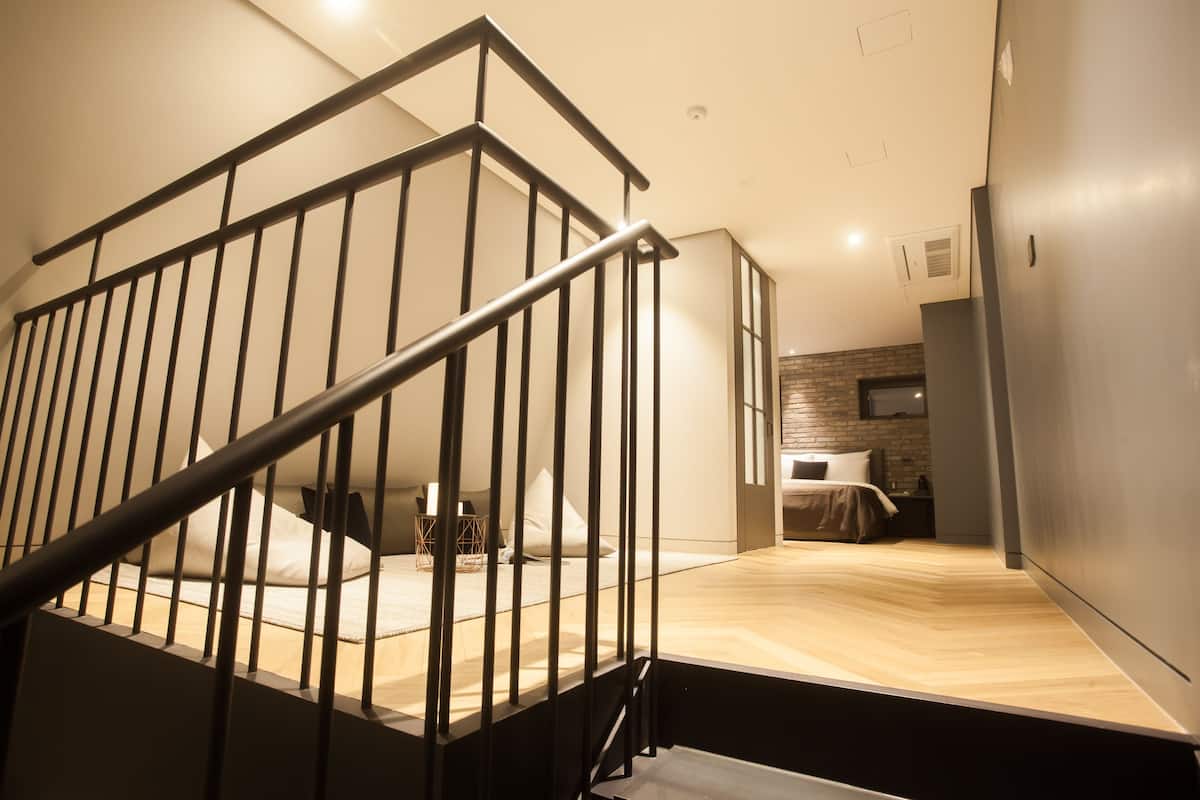 Une chambre moderne avec un plancher en bois, un lit avec une literie blanche, une table de chevet et un téléviseur intégré.