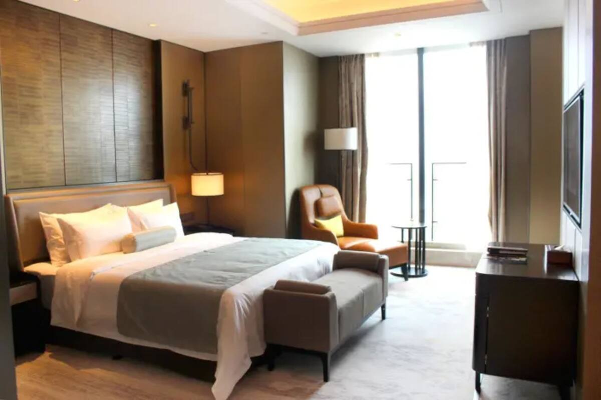 A hotel room with a large bed, a desk, a chair, and a TV.