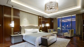 Una habitación de hotel moderna con una cama grande, un área de descanso y vistas a la ciudad.