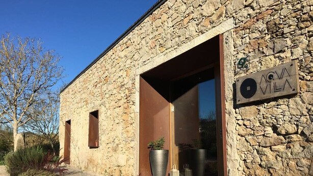 A stone building with an open entrance, a sign reading "AGVA VILA", and a potted plant outside. - Acquavilla House (Pombal)