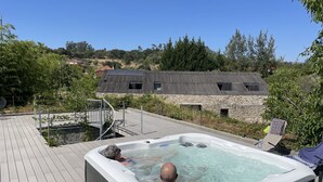 A hot tub on a wooden deck with a stone building in the background. - Acquavilla House (Pombal)