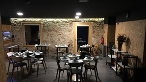 A restaurant with stone walls, wooden tables, and chairs. - Acquavilla House (Pombal)
