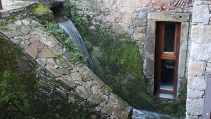 A stone building with a small window and a water feature. - Acquavilla House (Pombal)