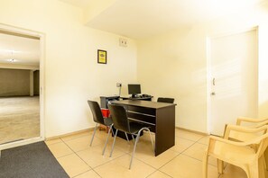 Un petit bureau avec un bureau, deux chaises noires et un ordinateur. Il y a une porte et un certificat encadré accroché au mur.