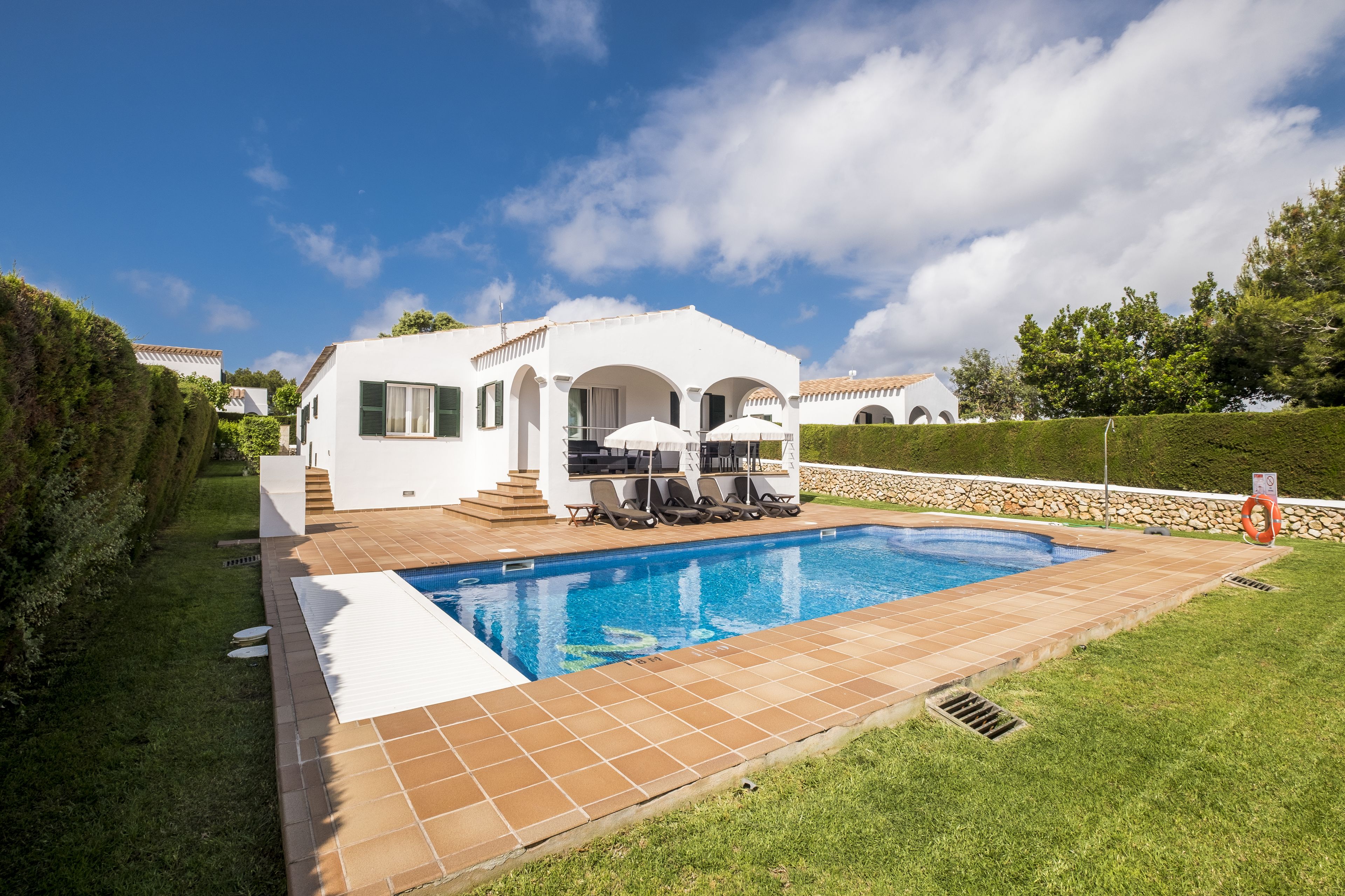 A modern villa with a swimming pool, outdoor seating, and a well-maintained garden.