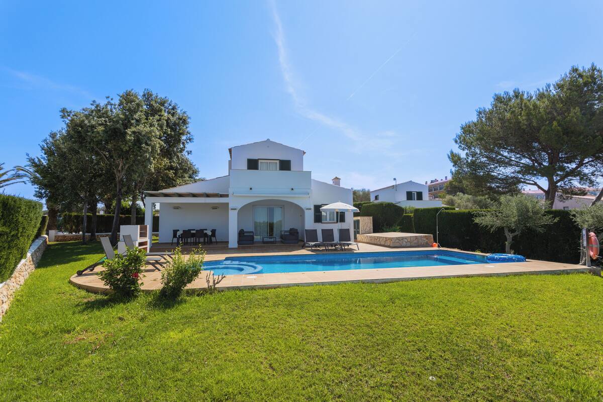 Una casa moderna con piscina, patio y césped bien cuidado.