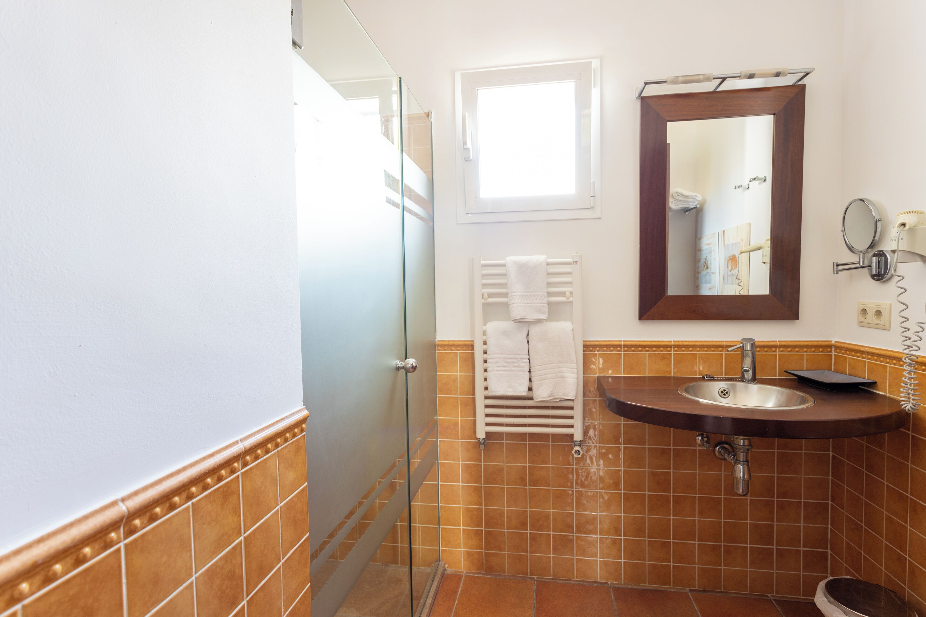 Ein Badezimmer mit Duschabtrennung aus Glas, einem Waschbecken mit Spiegel und einem Handtuchhalter.
