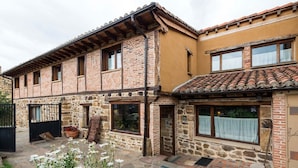A traditional stone building with a tiled roof, a wooden door, and a small window with a curtain. - Hotel Rural Piedra Abierta (San Cebrian de Muda)