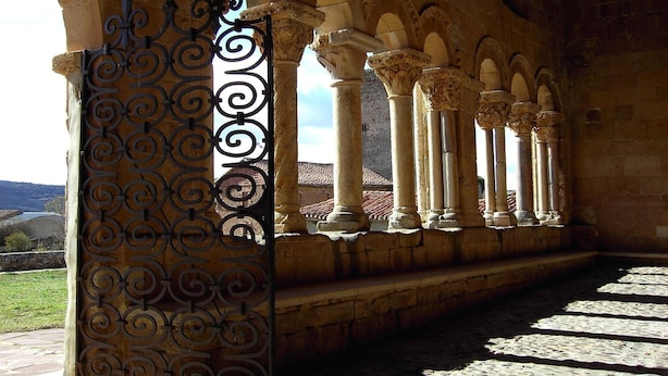 An arched corridor with columns and a decorative wrought iron gate. - Hotel Rural Piedra Abierta (San Cebrian de Muda)