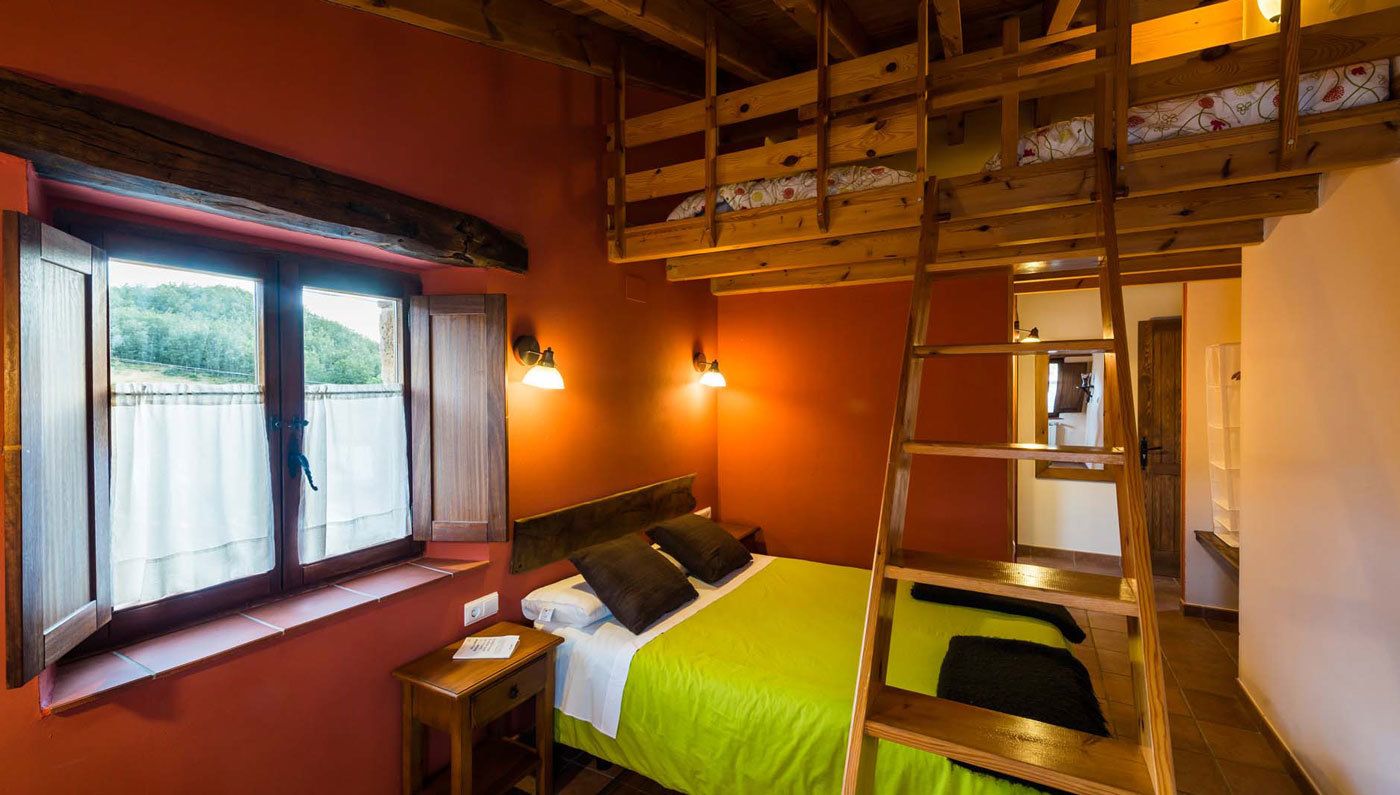 Una habitación con literas, una ventana con cortinas, una mesita de noche y una escalera.
