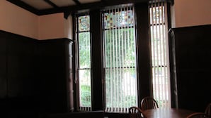 A dining area with a table and chairs, a dark-colored sofa, and a window with vertical blinds. - Aigburth Apartments - Ivanhoe (Liverpool)