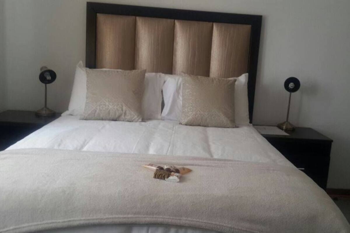 A neatly made bed with a headboard, two bedside tables with lamps, and a small decorative item on the bed.