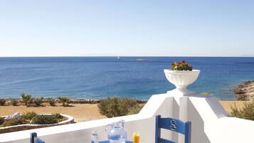 Enjoy a tranquil outdoor seating area with a table, two chairs, and a view of the sea and a distant island.
