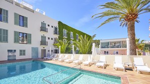 Una piscina con sillas de descanso y una palmera.