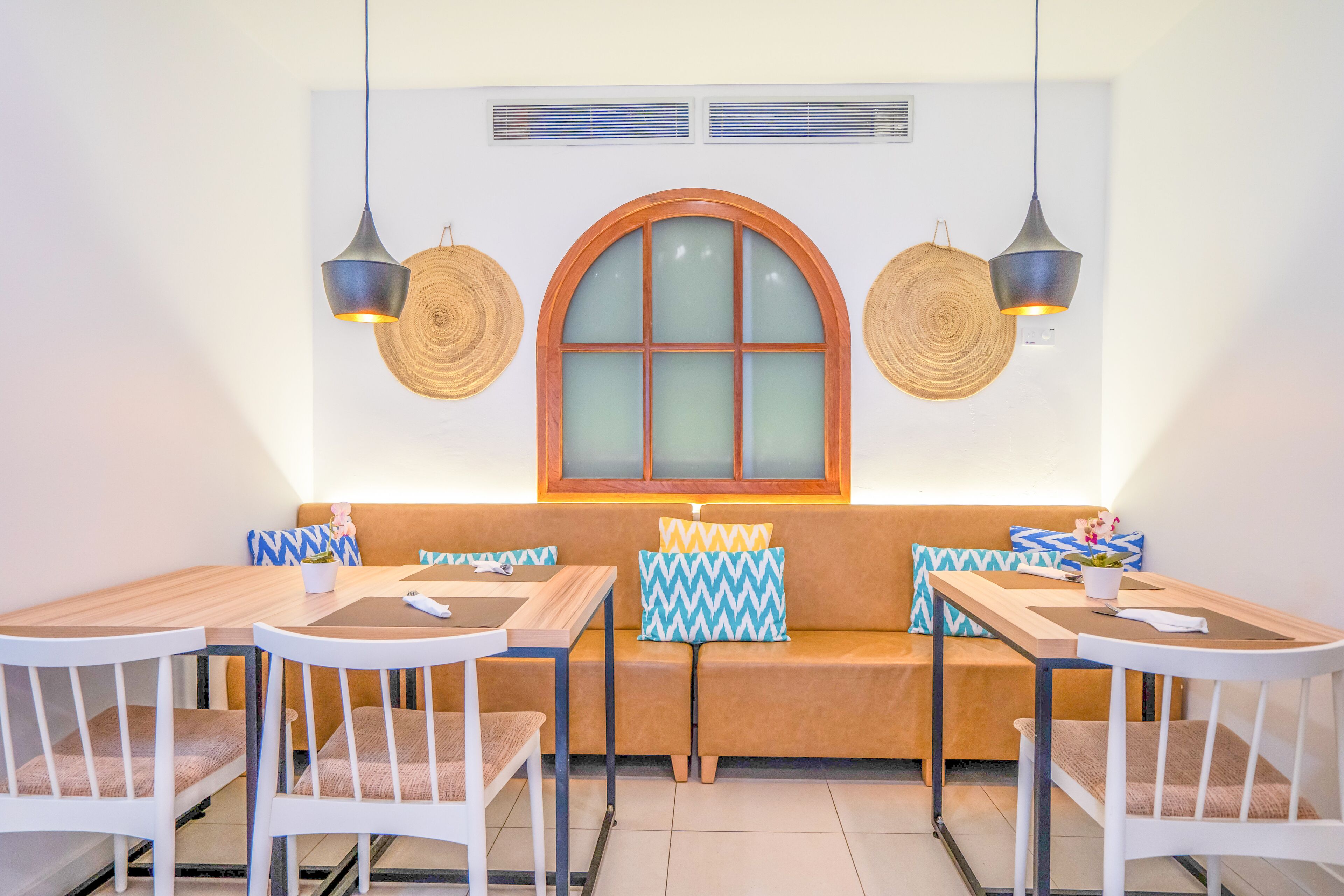 A dining area with a wooden table and chairs, a bench with cushions, and two pendant lights.