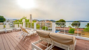 Una terraza con sillones blancos y vista al mar.