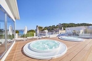 A rooftop deck with two hot tubs, lounge chairs, and a view of the sea. - Cupido Boutique Hotel (Calvia)