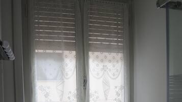 Ein Badezimmer mit Toilette, Waschbecken und einem Fenster mit Spitzenvorhängen.