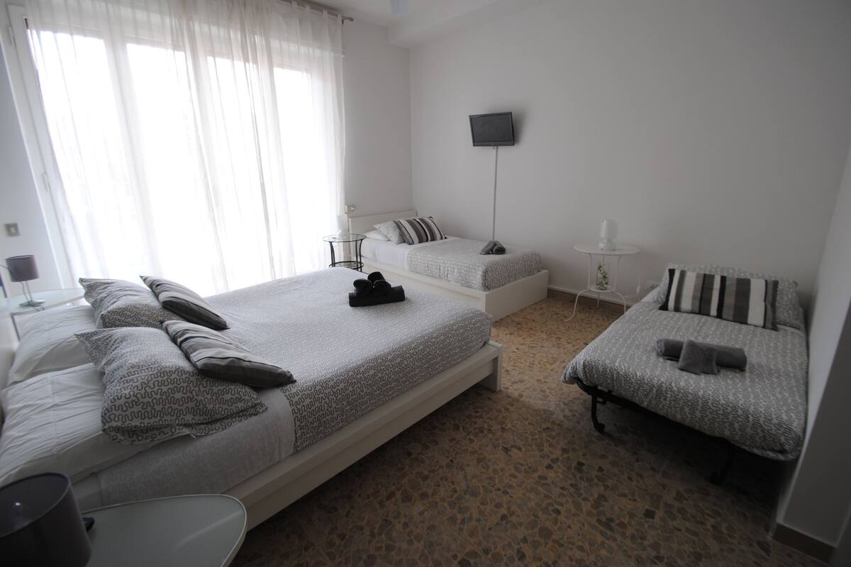 A bedroom with two beds, a TV, and a small table.