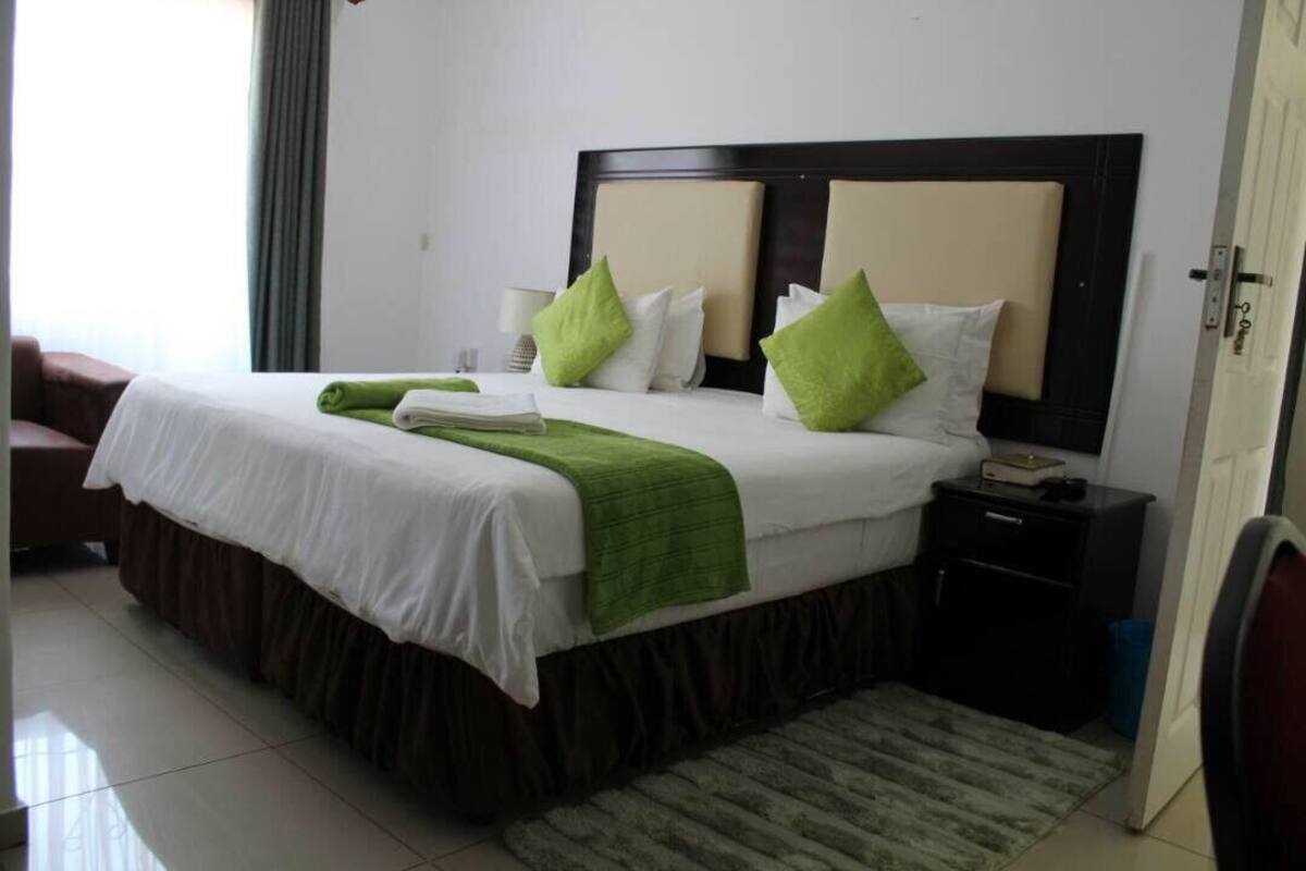 A hotel room with a large bed, a nightstand, a chair, and a door.