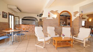 A dining area with brick walls, white chairs, and a tiled floor.