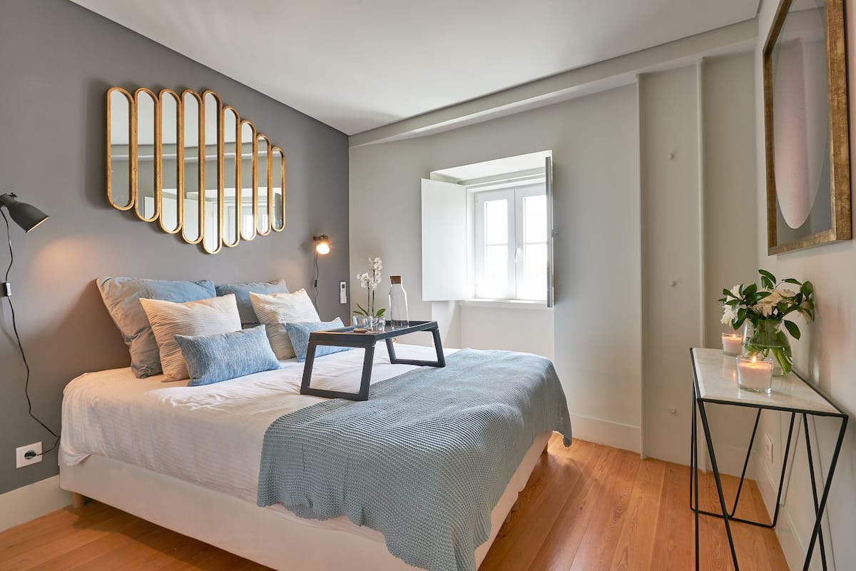 A modern bedroom with a bed, bedside table, and a large mirror on the wall.
