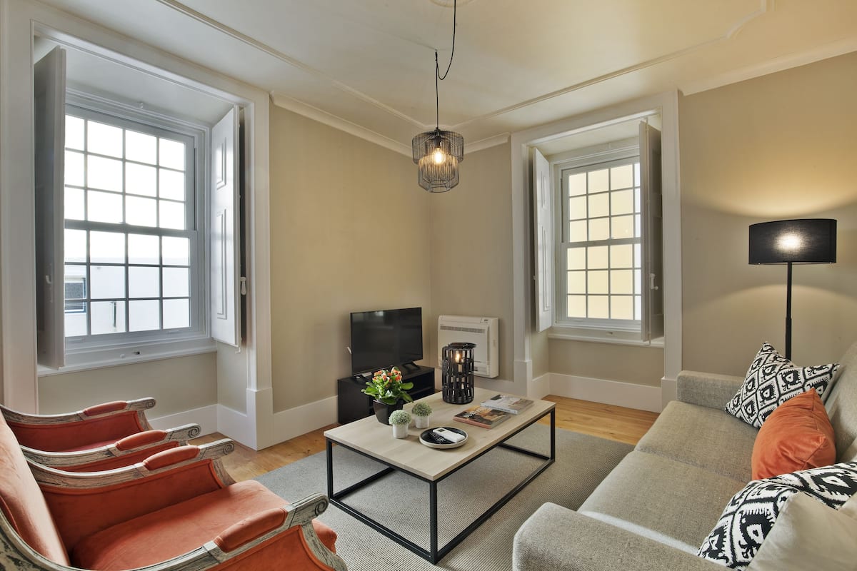 A living room with a sofa, chairs, a coffee table, a TV, and a lamp.