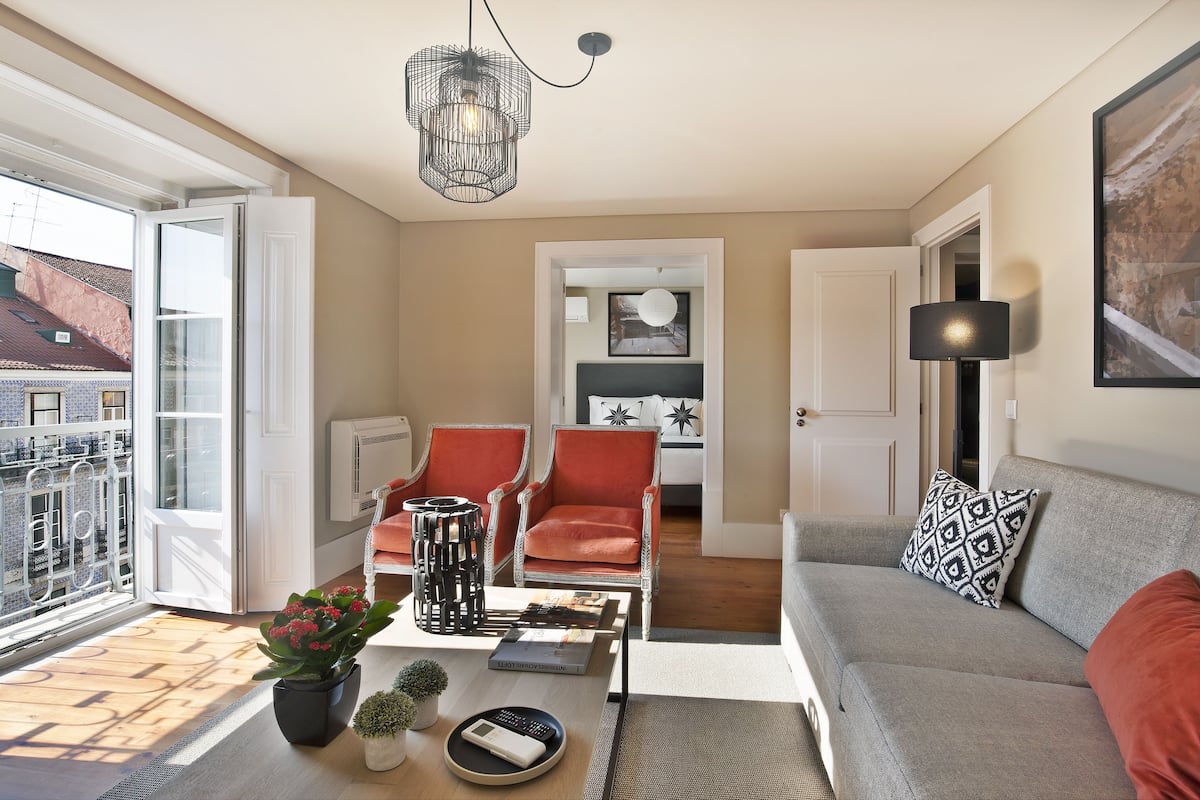 A modern living room with a sofa, two armchairs, a coffee table, and a potted plant.