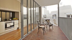 A balcony with a wooden floor, a chair, and a table. - Lisbon Five Stars Apartments - Bica 246 (Lisbon)