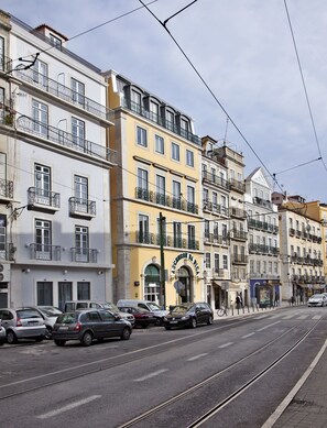 A street with tram tracks, parked cars, and multi-story buildings with balconies. - Lisbon Five Stars Apartments - Bica 246 (Lisbon)