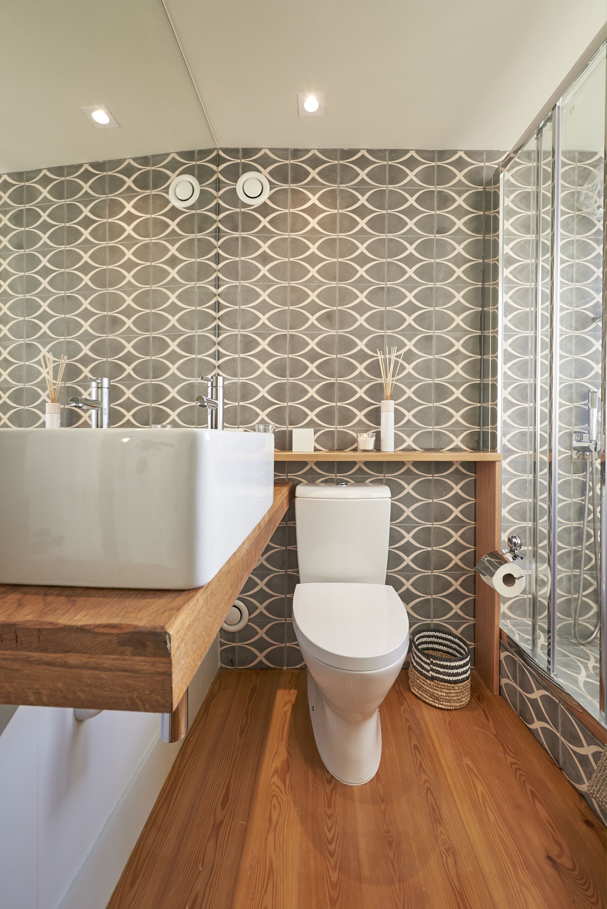 A modern bathroom with a wooden vanity, a freestanding bathtub, a toilet, and a glass shower enclosure.