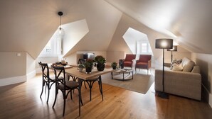 A spacious loft apartment with a dining area, a living room with a sofa and armchairs, and a large window providing natural light. - Lisbon Five Stars Apartments - Bica 246 (Lisbon)
