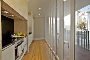 A modern kitchen with a wooden floor, a built-in stove, and a large window overlooking a balcony. - Lisbon Five Stars Apartments - Bica 246 (Lisbon)